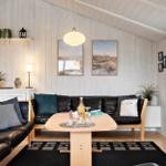 Wohnzimmer mit schwarzen Ledersofas, Holztisch und weißen Wänden.