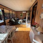 A room with dining area, sofa and wood paneling. Tables and chairs are present.