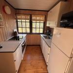 Kitchen with wood walls, fridge, stove, and windows