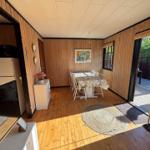 Dining room with table, chairs, and wood paneling. Access to kitchen and terrace.