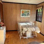 Dining room with wood paneling, table with chairs and window.