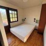 Bedroom with bed, window, and wooden floor.