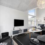 Wohnzimmer mit Kamin, Sofa, TV und großem Fenster.