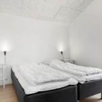 Schlafzimmer mit Doppelbett, zwei Nachttischen und Fenster zur Terrasse.