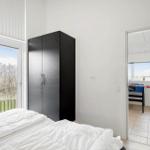 Schlafzimmer mit Bett, Kleiderschrank und Fenster. Durchgang zu einem Raum mit Tischfußball.
