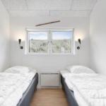 Zwei Betten mit weißen Laken, Fenster mit Strandblick und Wandlampen.