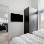 Schlafzimmer mit Bett, Kleiderschrank und Fernseher. Durchgang zum Wohnzimmer mit Sitzgelegenheit.