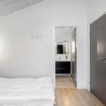 Schlafzimmer mit Bett, Schreibtisch und TV. Tür führt zum Badezimmer.