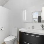Badezimmer mit Toilette, Waschbecken und Spiegel mit Beleuchtung.