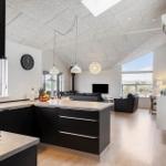 Moderne Küche mit Kücheninsel und Blick in Wohnzimmer mit Sofa und TV.