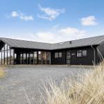 Moderne schwarze Hütte mit großem Glasbereich und Steinweg im Freien.