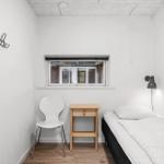 Ein Schlafzimmer mit Bett, Stuhl, Tisch und Fenster.