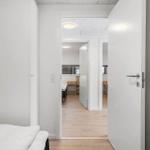 Schlafzimmer mit Blick in Wohnbereich mit Holzboden und Tisch
