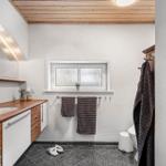 Badezimmer mit Holzoberfläche, Spiegel und Fenster. Handtuchhalter und Toilette sichtbar.
