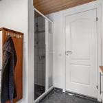 Dusche mit Glaswand, weiße Tür und Holzregale