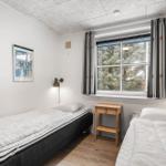 Zwei Einzelbetten, ein Nachttisch und ein Fenster mit Blick auf Bäume.