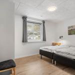 Zwei Schlafplätze, Fenster mit grauen Vorhängen, Holzboden und Wandbild.