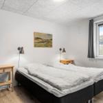 Schlafzimmer mit Doppelbett, zwei Nachttischen und Fenster.