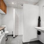 Badezimmer mit Waschmaschine, Toilette und Dusche.