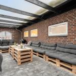 Terrasse mit Sitzgelegenheiten aus Paletten und Backsteinwand