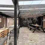 Terrasse mit Sitzgelegenheiten, Tisch und Pergola unter freiem Himmel.