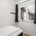 Schlafzimmer mit Bett, Fenster und Gardinen.