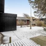 Schneebedeckter Garten mit Holzterrasse und rotem Backsteinhaus im Hintergrund.
