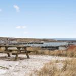Holztisch auf sandigem Boden mit Blick auf Hafen und Meer.