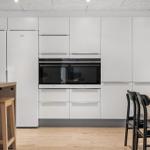 Moderne Küche mit weißen Schränken, integriertem Kühlschrank und Backofen.