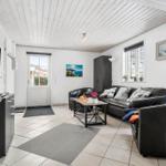 Living room with black leather furniture, TV, and window with view.