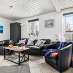 Living room with black leather furniture, wooden table, and windows.
