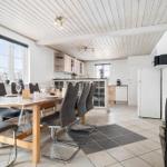 Dining room with wooden table, chairs, and kitchen area in the background.