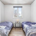 Two single beds with patterned bedspreads, a window, and a lamp.