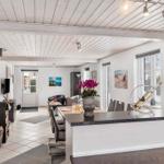 Entrance area with dining space, fireplace, and windows. Table with chairs and flowers.