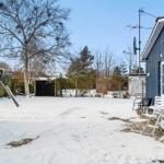 Snow-covered garden with blue house and white table set.