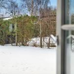 Snow-covered garden with fence and bushes in the background