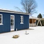Blue-painted house with snow-covered garden and playground