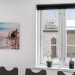 Window with view to outside, wall picture with beach motif and plants on windowsill.