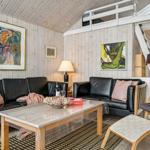 Wohnzimmer mit zwei schwarzen Sofas, Holztisch und Gemälden an den Wänden.