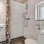 Badezimmer mit Dusche, Waschbecken und Toilette. Fenster mit Milchglas.