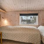 Schlafzimmer mit Holzwand, Bett und Fenster zum Außenbereich.
