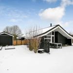 Schwarz-weißes Haus mit Schneebedecktem Garten und Terrasse.
