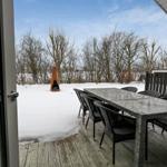Terrasse mit Tisch und Stühlen, Schnee im Hintergrund, Holzdecke und Feuerstelle.
