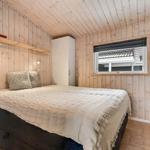 Schlafzimmer mit Holzwand, Bett, Kleiderschrank und Fenster.