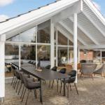 Patio with table and chairs under white roof. Large windows show living area.