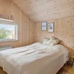 Bedroom with wooden walls, bed, window, and nightstand.