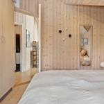 Bedroom with wooden wall, bed, mirror, and wardrobe.