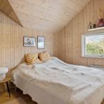 Bedroom with wooden walls, bed, window, and nightstand.