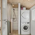Shower with curtain and stacked washer-dryer unit.