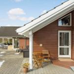 Wooden house with terrace, garden furniture, and snow on the ground.